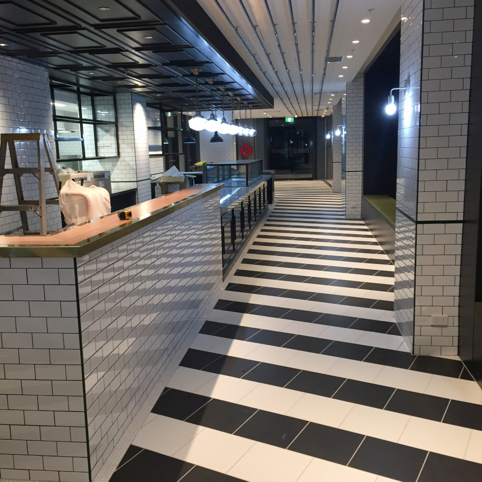 Commercial tiling fitout with white tiled walls and black and white patterned floor tiles