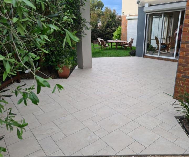 Outdoor tiled patio beside a modern home and garden seating area